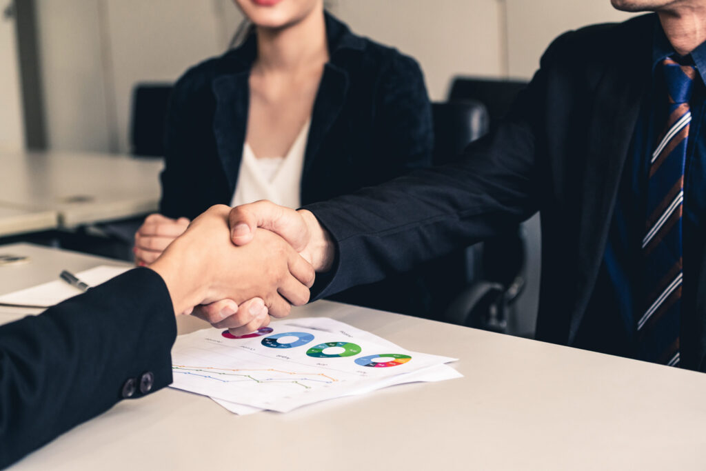 Selling a Hiome in Colorado: Business people agreement concept. Businessman and Asian businesswoman do handshake in the office.