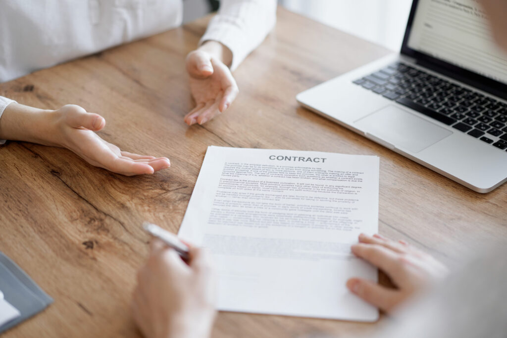 Selling a Home in Colorado: Business people signing contract papers while sitting at the wooden table in office, closeup. Partners or lawyers working together at meeting. Teamwork, partnership, success concept